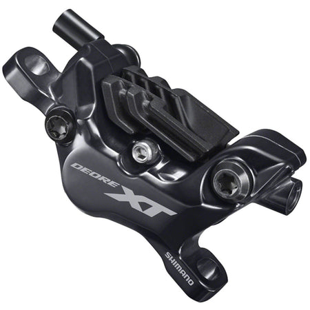 Shimano Deore XT BR-M8100 series disc brake calipers mounted on a bike, showcasing hydraulic brake caliper design and branding.