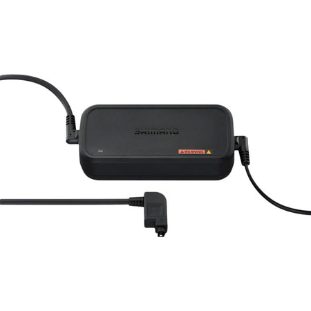 Shimano Steps eBike battery charger connected to a charging port, showing a compact black charger for e-bike batteries.